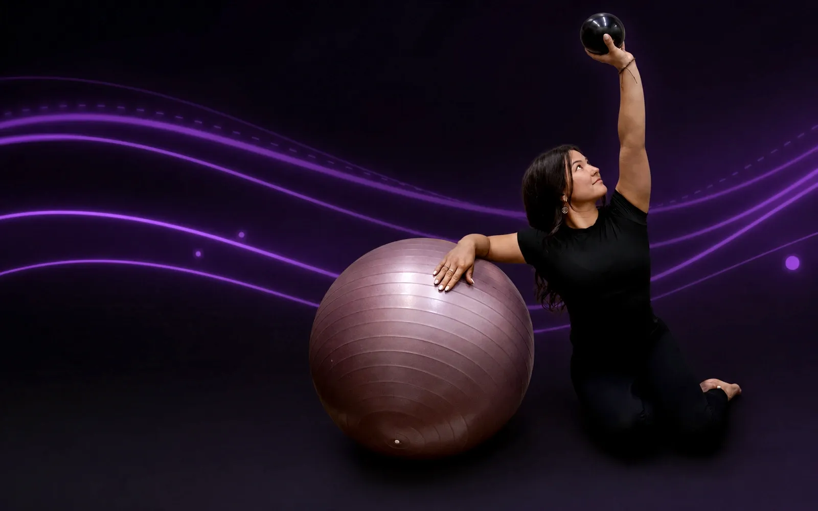 Coach Kiarra exercising beside a stability ball against a dark purple movement-inspired background.